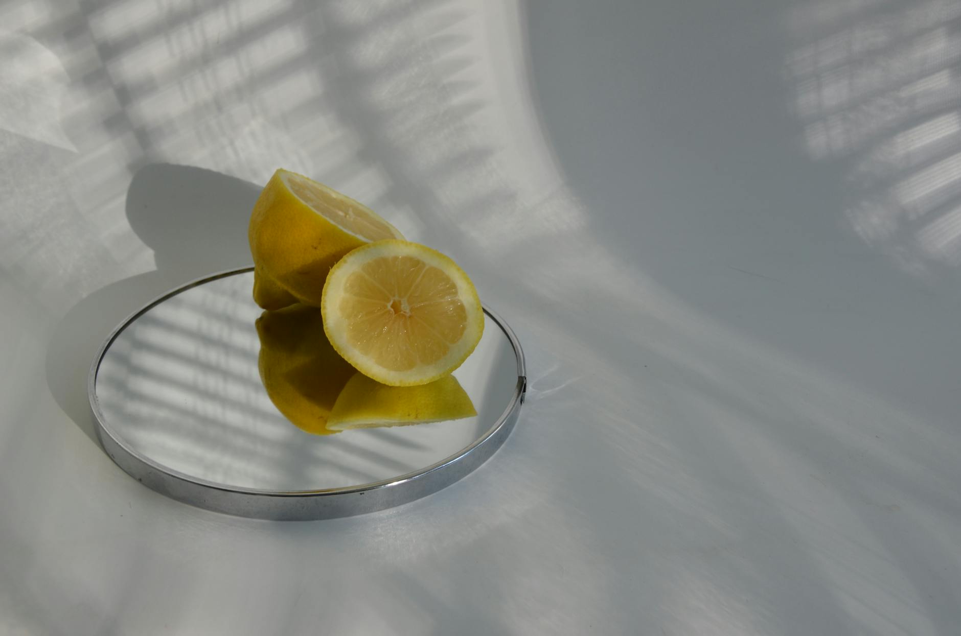 Mão feminina segurando um limão fresco contra fundo rosa suave, cercado por frutas adicionais