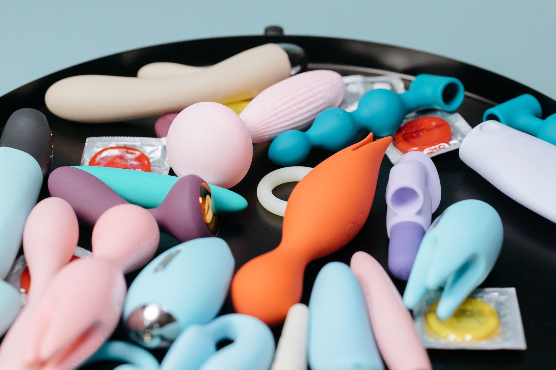 Mão segurando um vibrador azul contra fundo roxo, expressando sensualidade e amor próprio