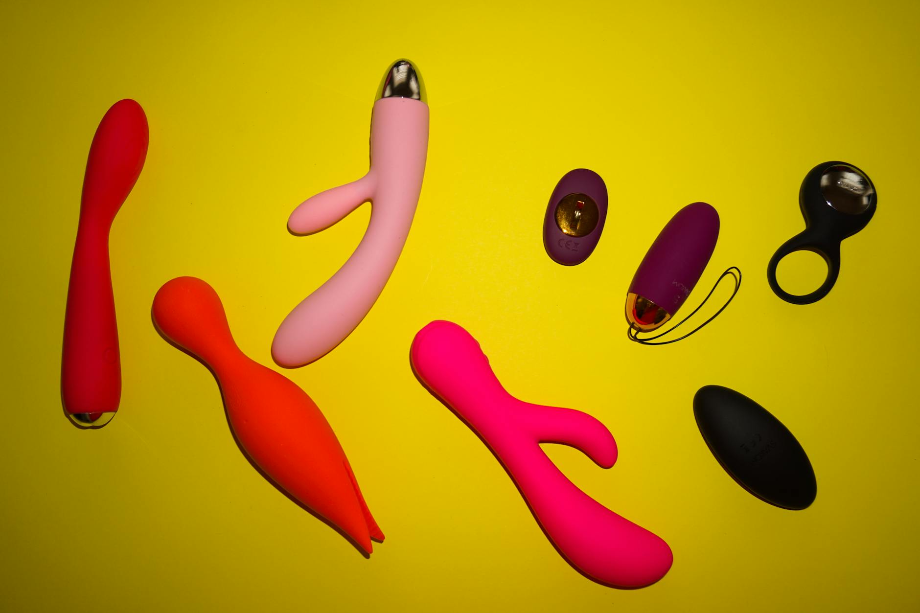 Vibrant arrangement of various clitoral vibrators and toys on a bright yellow surface